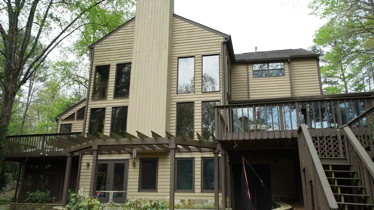 Before: Back of a two-story Roswell home with a tall chimney and deck