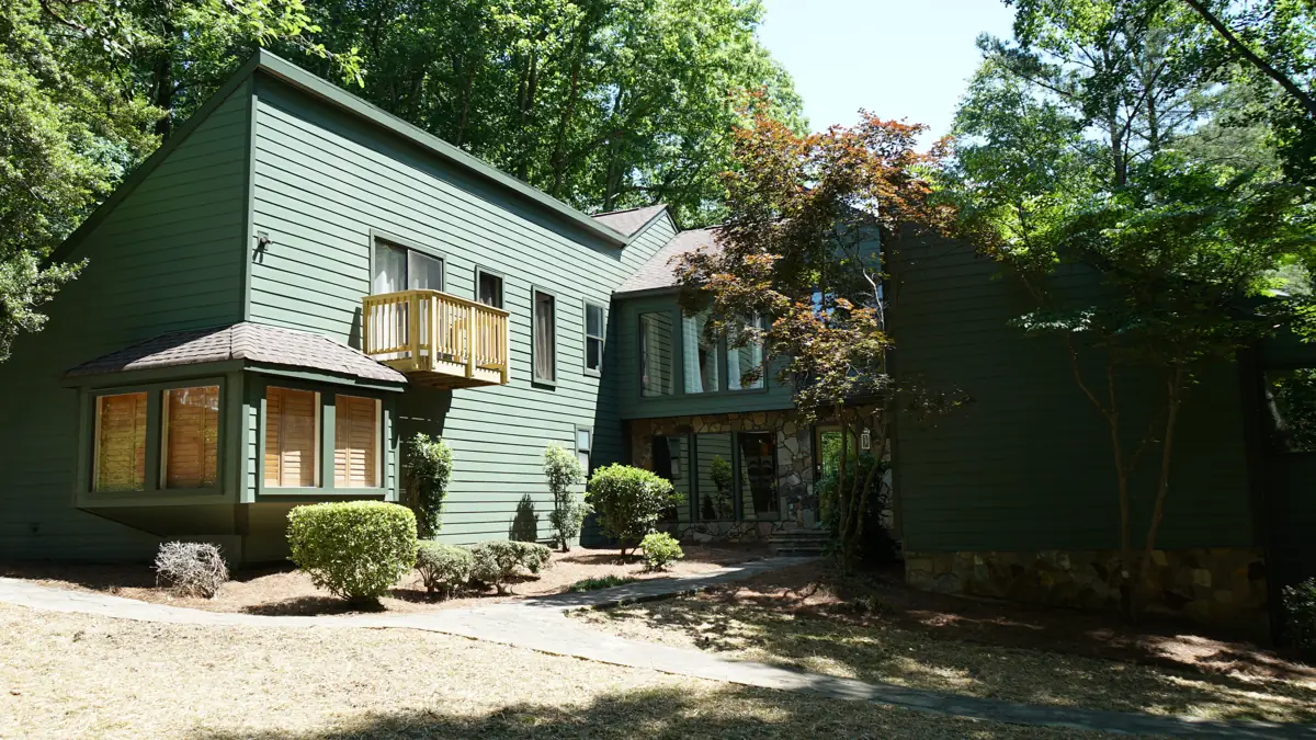 Two-story Roswell, GA home on a wooded lot after new siding in deep green