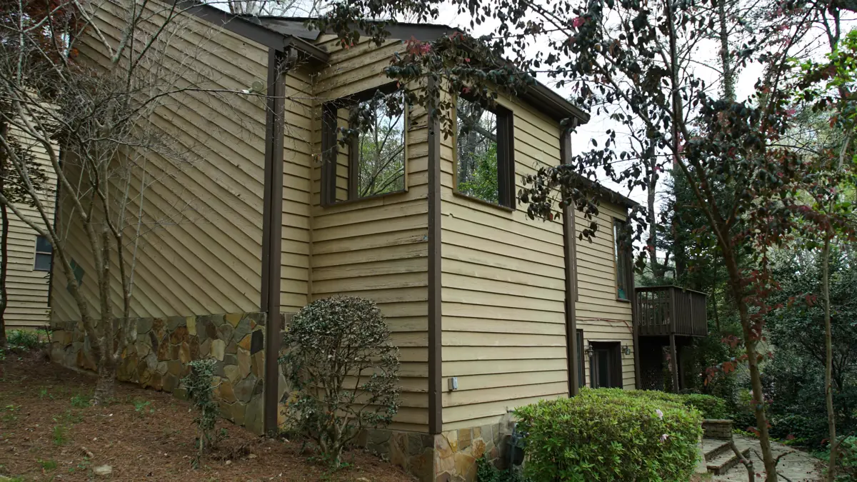 Before: Side of a two-story Roswell home with a stone base